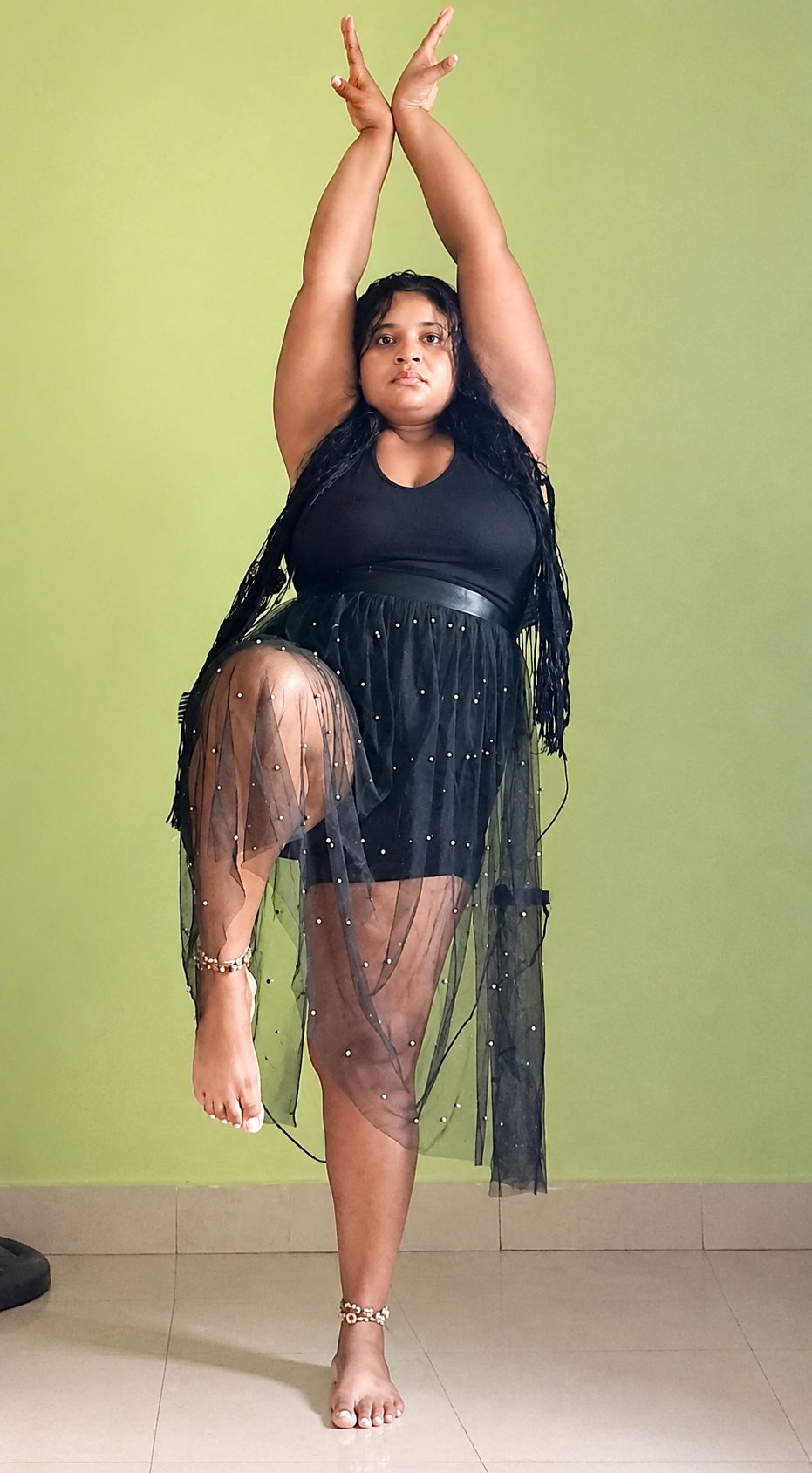 A woman standing with both arms stretched overhead, mid-practice.